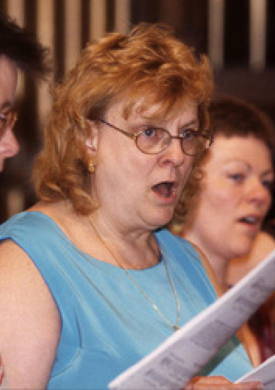 Image from The Amasong Chorus Singing Out. A close up of women holding sheet music and singing.