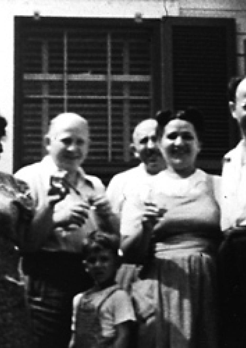Black-and-white photo of five Eastern European Jewish adults and one child standing in a row and smiling for the camera.