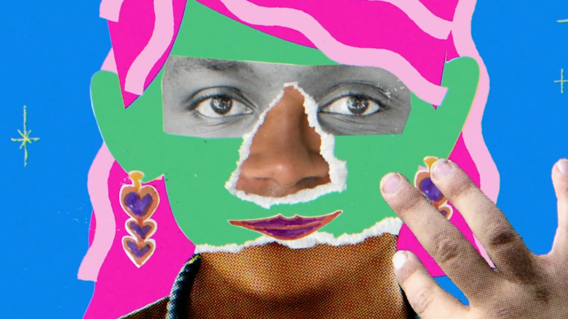 A still from Mama Has A Mustache. A person with brown skin faces the camera and has one hand raised up near their face. The photo is collaged over with eyes from a black and white photo, torn green paper over much of the face, pink hair, dangly heart earrings drawn in marker, and a nose and mouth from other photos.